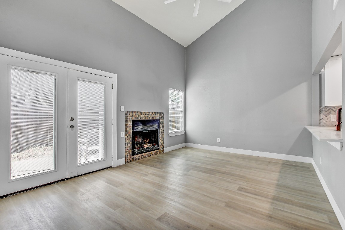 1010 West Rundberg Lane, Unit 24 Austin, TX 78758 - Photo 4 of 24 Unfurnished living room with high vaulted ceiling, ceiling fan, light wood-style floors, french doors, and a fireplace