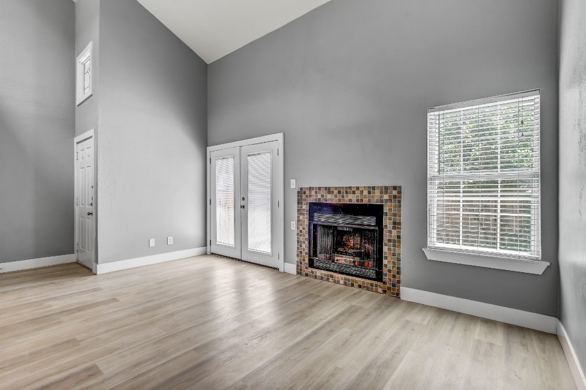 1010 West Rundberg Lane, Unit 24 Austin, TX 78758 - Photo 5 of 24 Unfurnished living room featuring high vaulted ceiling, wood finished floors, a tile fireplace, and baseboards