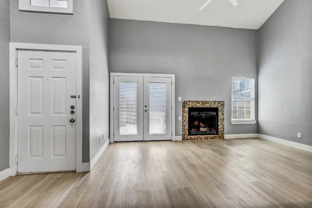 an empty room with wooden floor fireplace and windows