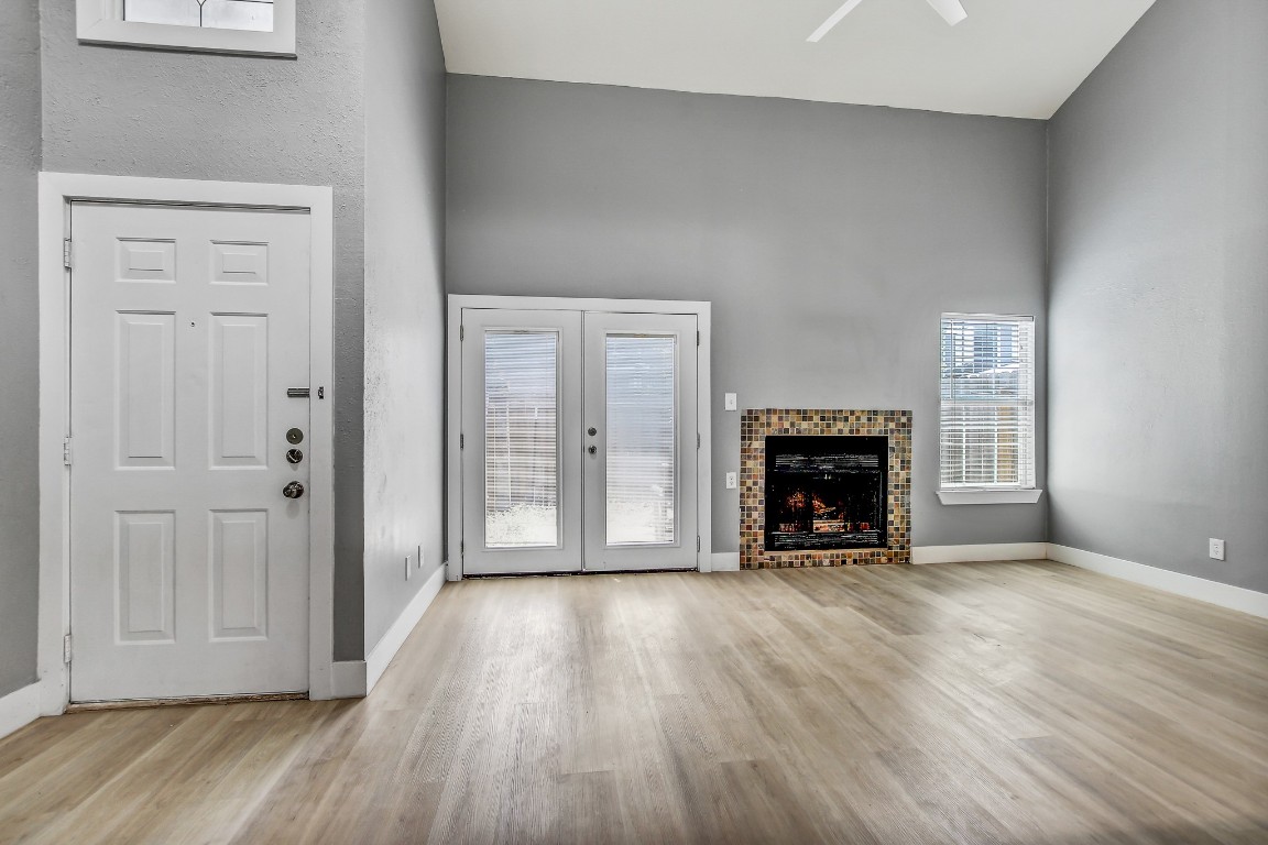 1010 West Rundberg Lane, Unit 24 Austin, TX 78758 - Photo 6 of 24 Unfurnished living room featuring wood finished floors, baseboards, ceiling fan, a towering ceiling, and a fireplace