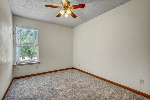 an empty room with a window and a fan