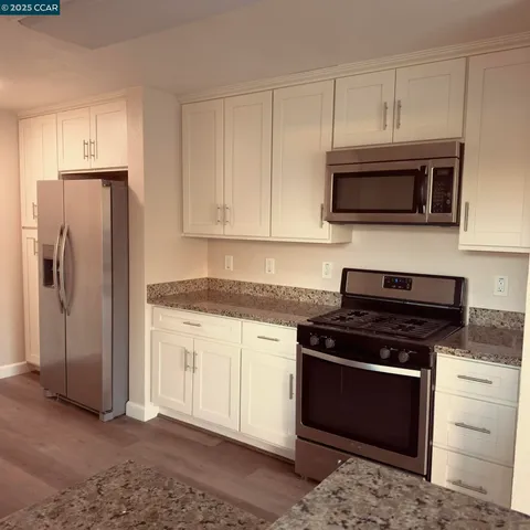 a kitchen with stainless steel appliances granite countertop a stove microwave and refrigerator