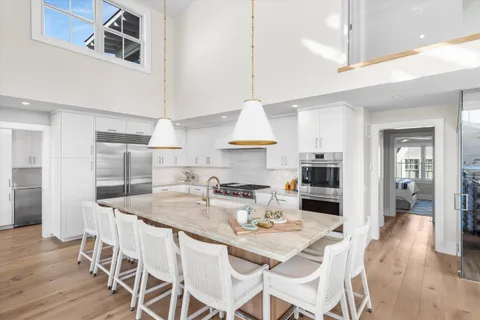 a kitchen with stainless steel appliances kitchen island granite countertop a dining table chairs and a refrigerator