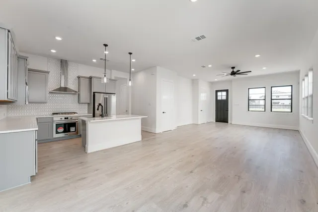 a view of kitchen with kitchen island wooden floor center island and stainless steel appliances