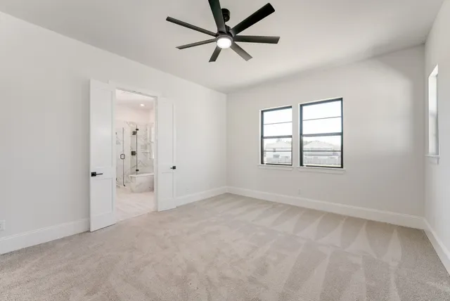 an empty room with windows and ceiling fan