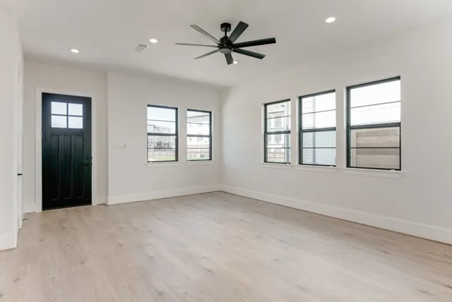 an empty room with windows and ceiling fan