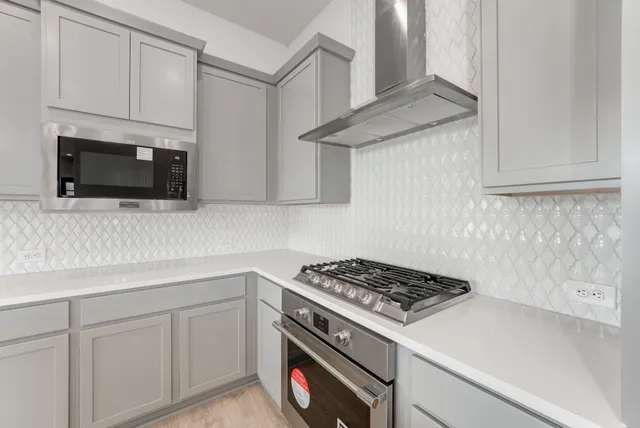 a kitchen with stainless steel appliances white cabinets and a stove top oven