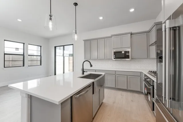 a kitchen with stainless steel appliances granite countertop a sink a stove a refrigerator cabinets and a window