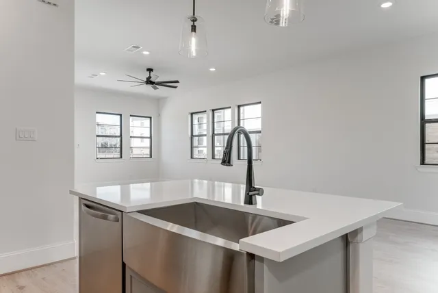 a kitchen with stainless steel appliances granite countertop a sink dishwasher and a refrigerator with wooden floor