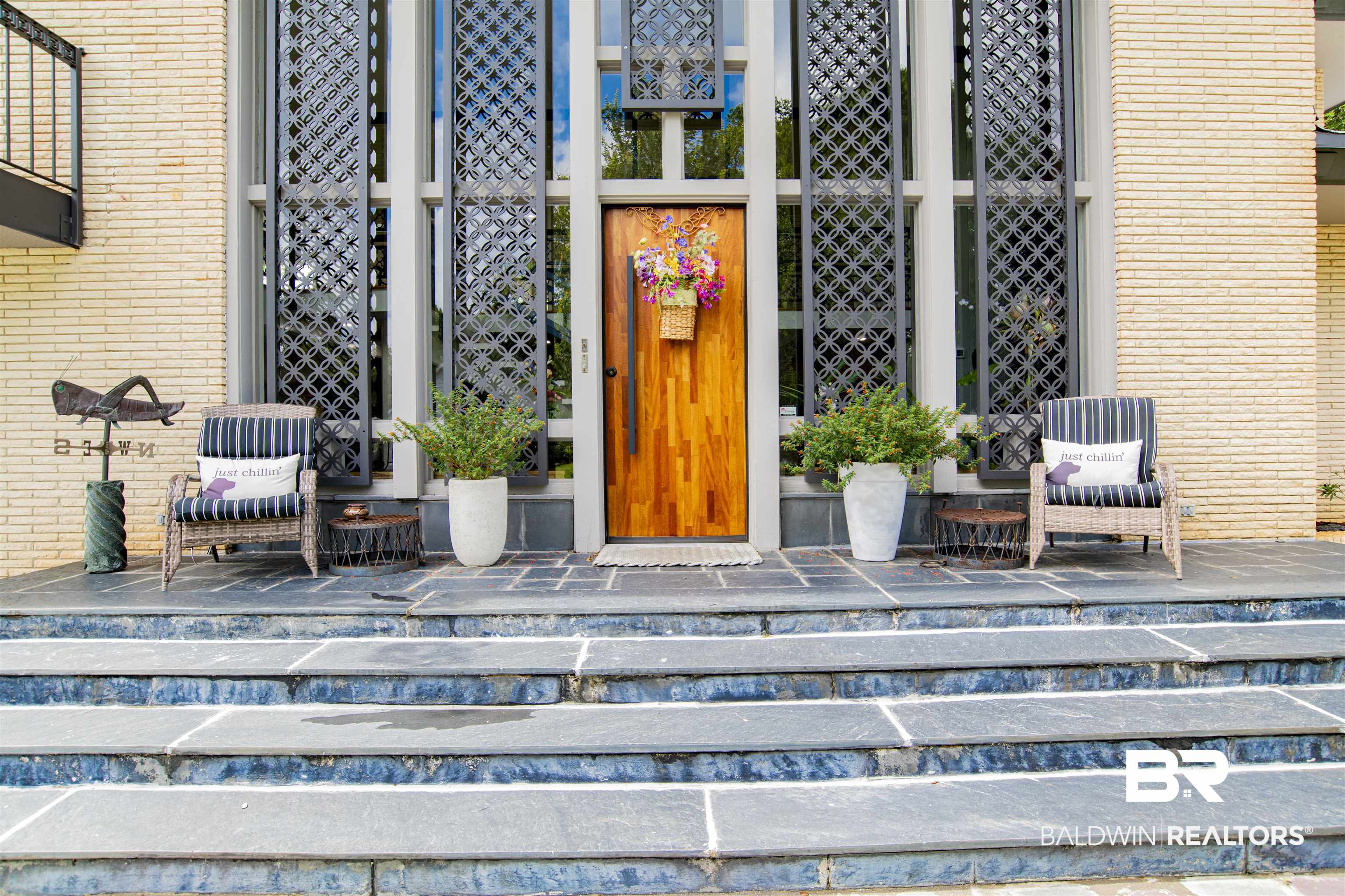 809 Bernard Circle Mobile, AL 36693 - Photo 47 of 75 Natural wood-finish entry door with dark hardware, flanked by tall decorative metal screens and large windows