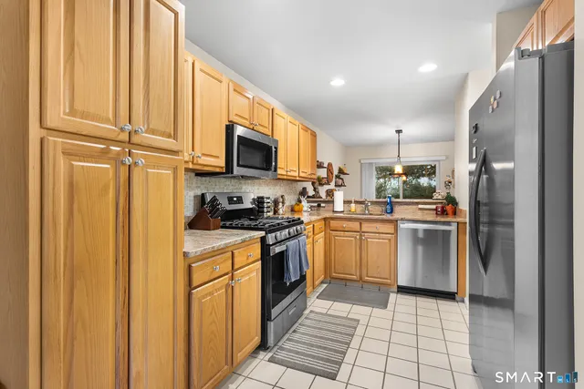 a kitchen with stainless steel appliances granite countertop a refrigerator a stove top oven a sink and dishwasher