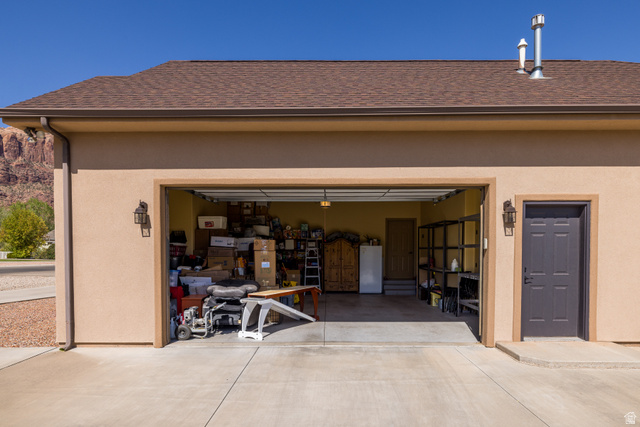 4635 East Sunny Acres Lane Moab, UT 84532 - Photo 35 of 56 Attached garage featuring a light stucco exterior, brown shingle roof, and concrete driveway