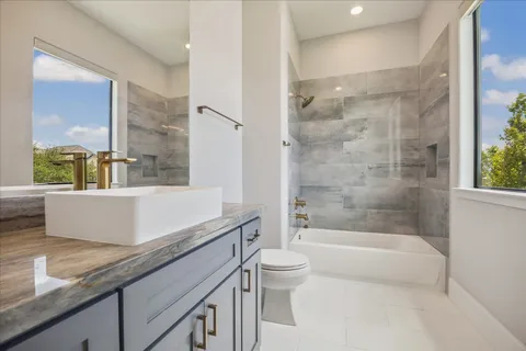 a bathroom with a granite countertop bathtub sink vanity mirror and toilet