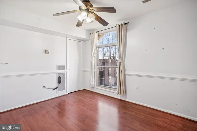 an empty room with wooden floor closet and windows