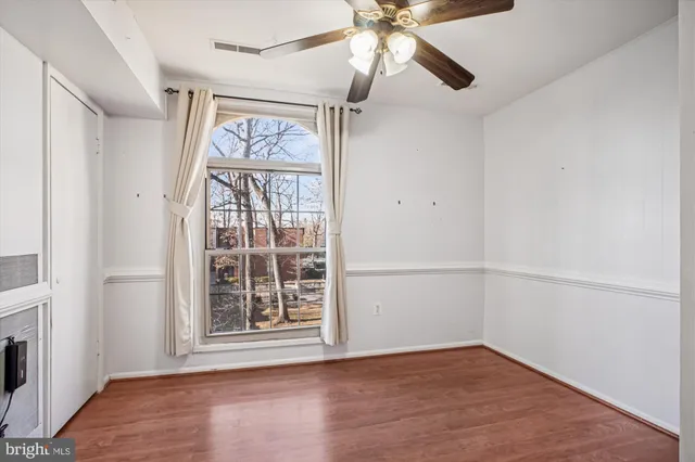 an empty room with wooden floor fan and windows