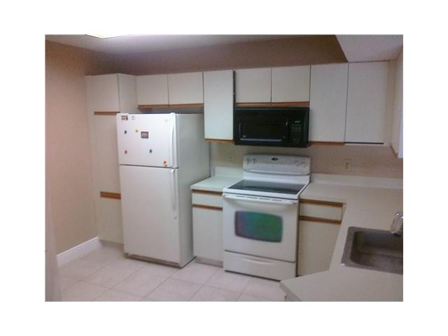 8977 Wiles Road, Unit 2105 Coral Springs, FL 33067 - Photo 3 of 7 a kitchen with a refrigerator sink and cabinets