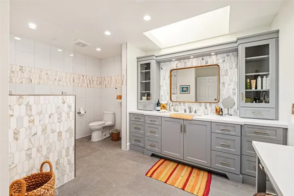 a large bathroom with a double vanity sink toilet and a large mirror