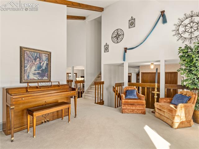 5258 Willowbrook Road Colorado Springs, CO 80917 - Photo 8 of 35 Sitting room featuring beamed ceiling, stairway, high vaulted ceiling, and carpet