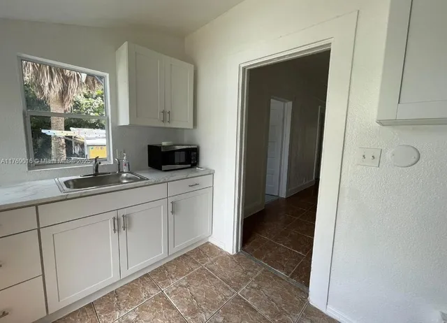 a kitchen with granite countertop white cabinets and sink
