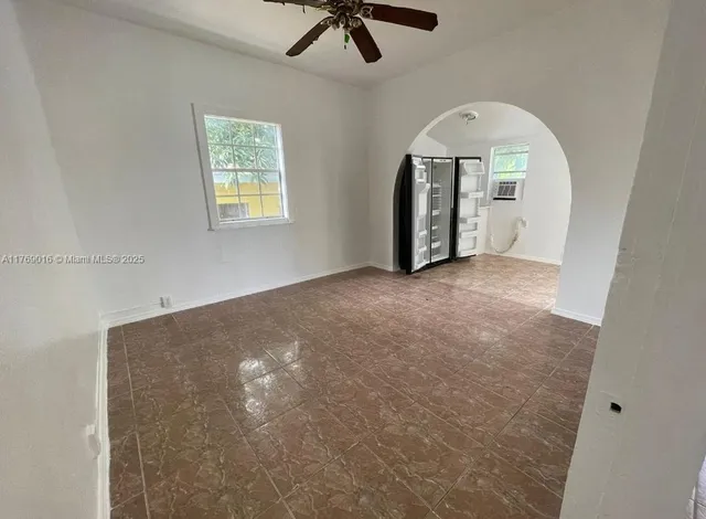an empty room with chandelier fan and windows