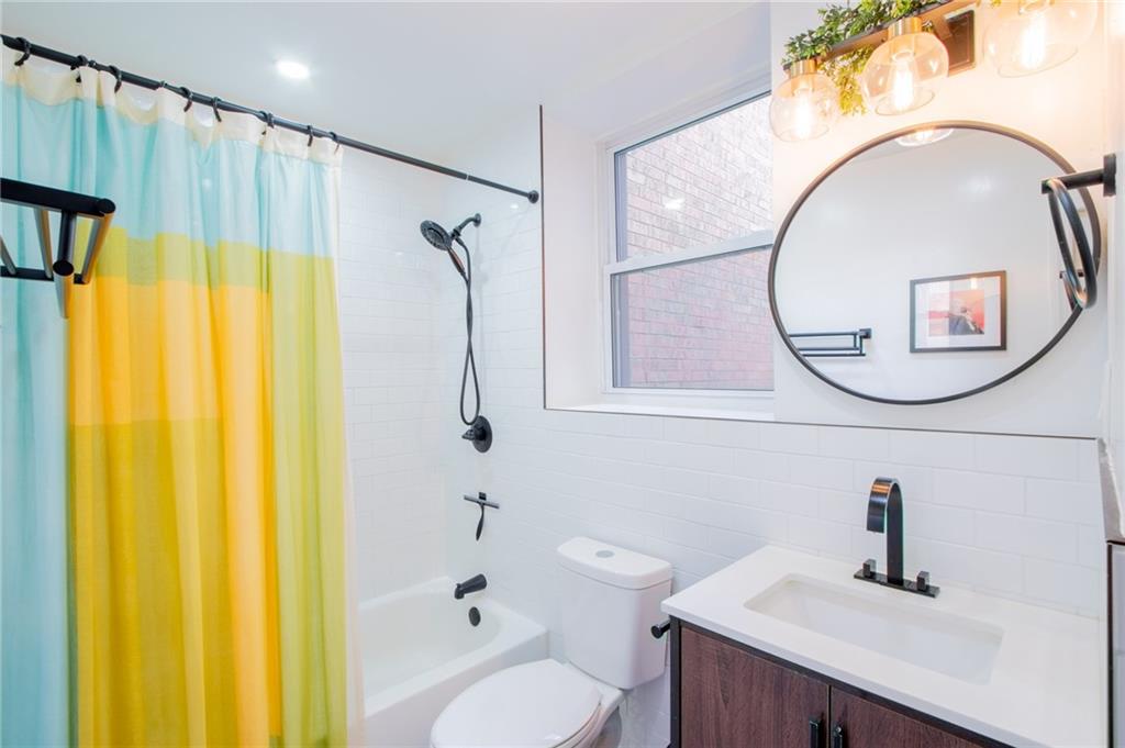 10104 4th Avenue, Unit 2B Brooklyn, NY 11209 - Photo 10 of 27 a bathroom with a sink a toilet and a mirror