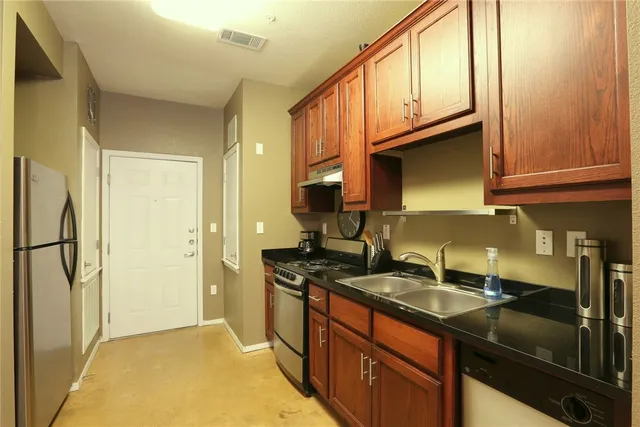 a kitchen with stainless steel appliances granite countertop a sink stove and refrigerator