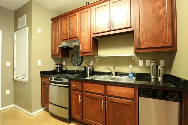 a kitchen with stainless steel appliances granite countertop a stove a sink and a microwave