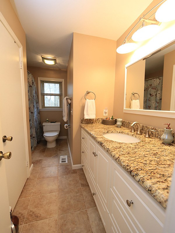 6552 Keystone Drive Raleigh, NC 27612 - Photo 14 of 25 The Main Level Shared Hall Bath features a Large Granite Vanity with Storage, Linen Closet, Tile Floors and Tile Shower/Tub Surround. Bathroom