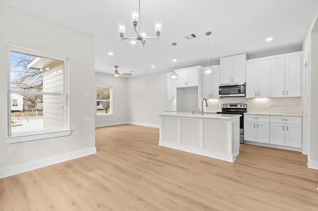 a kitchen with stainless steel appliances kitchen island granite countertop a stove a sink and white cabinets with wooden floor