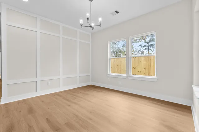 an empty room with chandelier fan and windows
