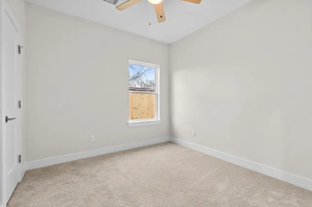 an empty room with a window and a fan