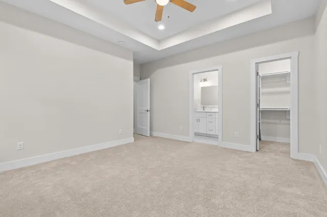 an empty room with chandelier fan and windows