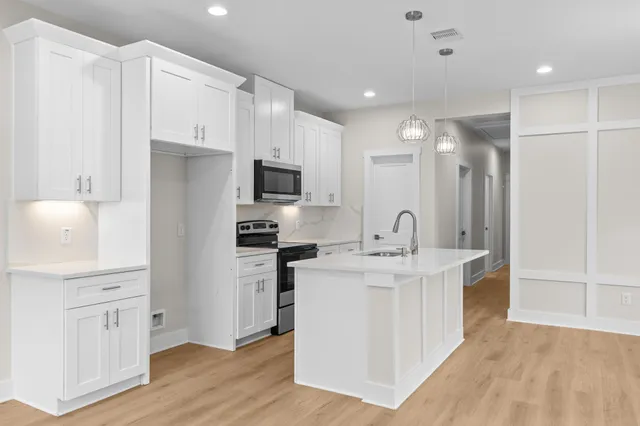 a kitchen with white cabinets and stainless steel appliances