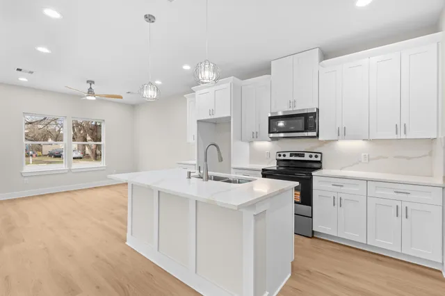 a kitchen with stainless steel appliances granite countertop a sink dishwasher a stove and a refrigerator with wooden floor