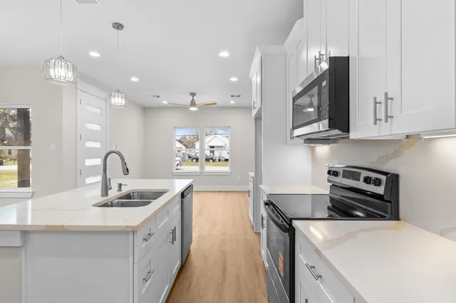 a kitchen with kitchen island granite countertop a sink stainless steel appliances and white cabinets