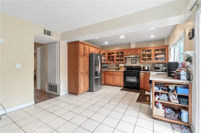 a kitchen with stainless steel appliances kitchen island granite countertop a refrigerator and a stove top oven