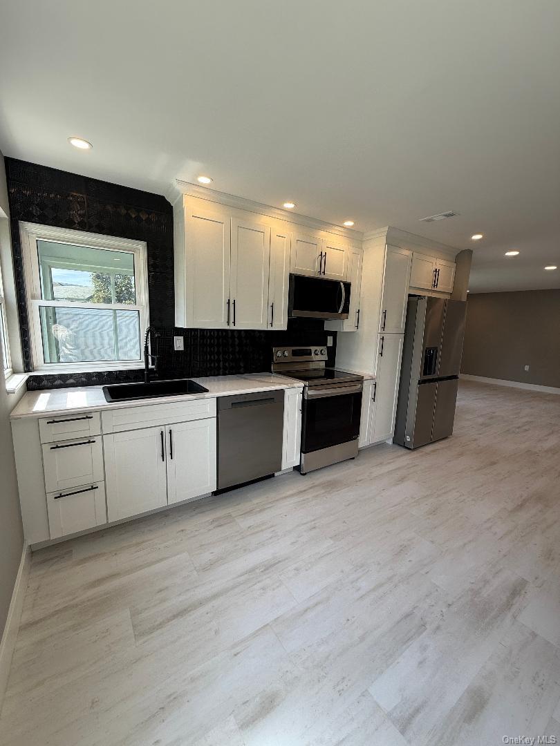 379 Larchmont Court Ridge, NY 11961 - Photo 4 of 17 a kitchen with a sink cabinets and stainless steel appliances
