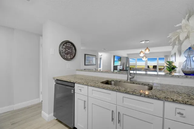 a kitchen with granite countertop a sink a stove and cabinets