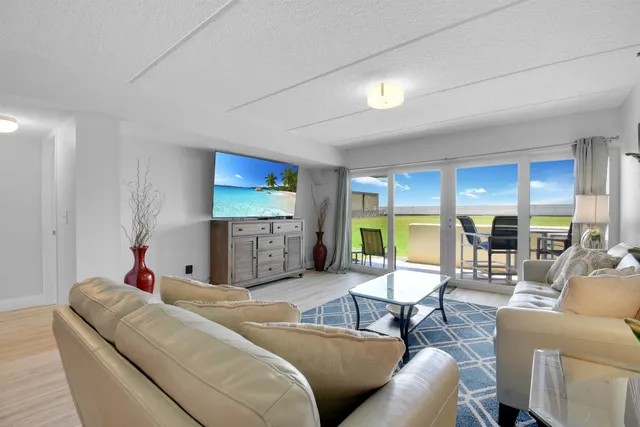 a living room with furniture kitchen view and a large window