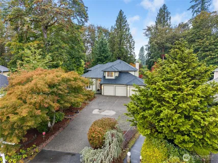 a front view of a house with a yard and covered by trees