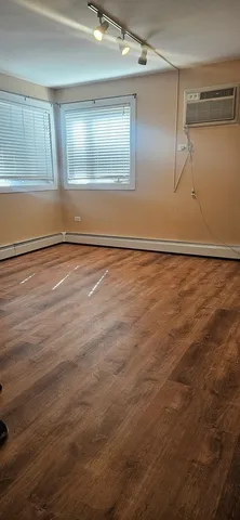 a view of an empty room with wooden floor and windows