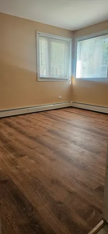 a view of an empty room with wooden floor and windows