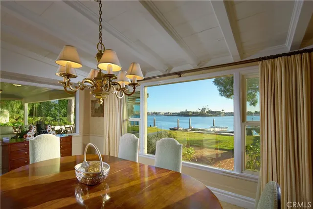 a view of a dining room with furniture a chandelier and large windows