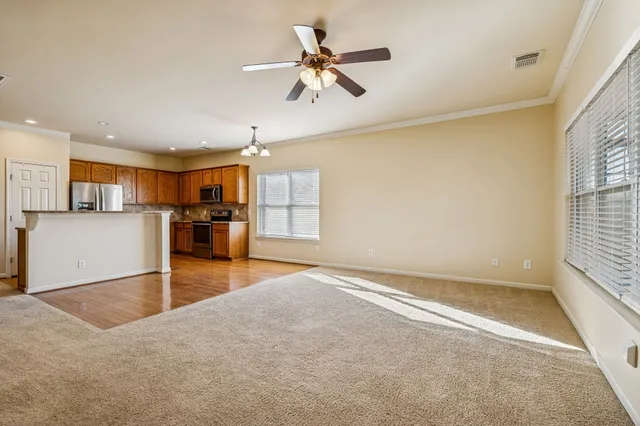 an empty room with chandelier fan and windows