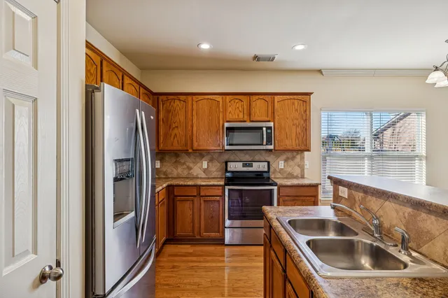 a kitchen with stainless steel appliances granite countertop a refrigerator sink and stove