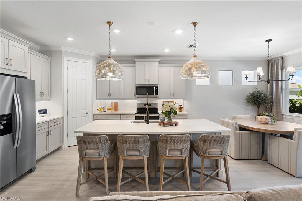 394 Deauville Loop Naples, FL 34114 - Photo 6 of 50 a kitchen with stainless steel appliances a dining table chairs stove and refrigerator
