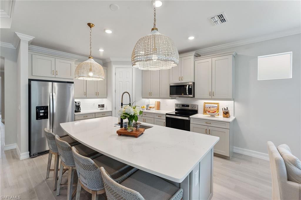 394 Deauville Loop Naples, FL 34114 - Photo 7 of 50 a kitchen with refrigerator cabinets dining table and chairs