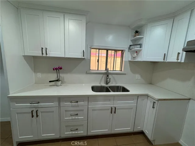 a kitchen with white cabinets and sink