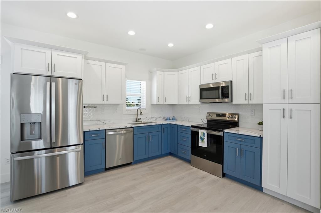 1 Fairview Boulevard Fort Myers Beach, FL 33931 - Photo 13 of 48 a kitchen with stainless steel appliances granite countertop a refrigerator stove a sink and white cabinets