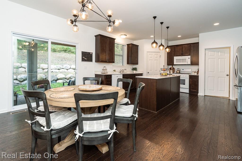 201 Beechview Drive Rochester, MI 48306 - Photo 14 of 49 Dark wood-finish flooring throughout, kitchen island with solid surface countertop, dark wood cabinetry, white appliances, and pendant lighting